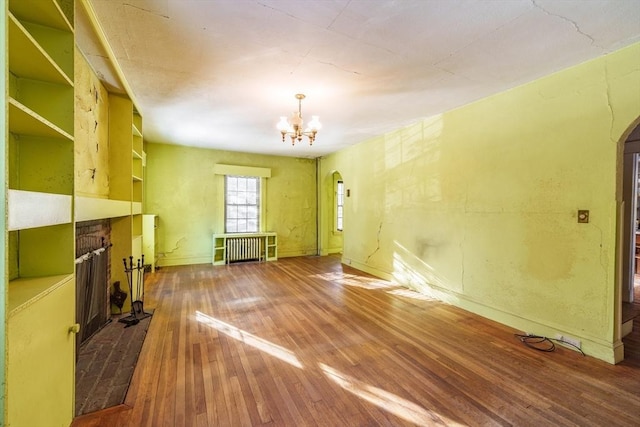 unfurnished living room with hardwood / wood-style flooring, radiator, and a chandelier