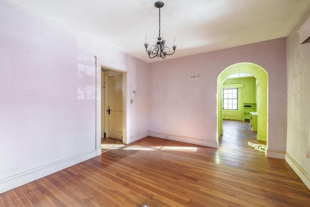 unfurnished room featuring a notable chandelier and hardwood / wood-style flooring