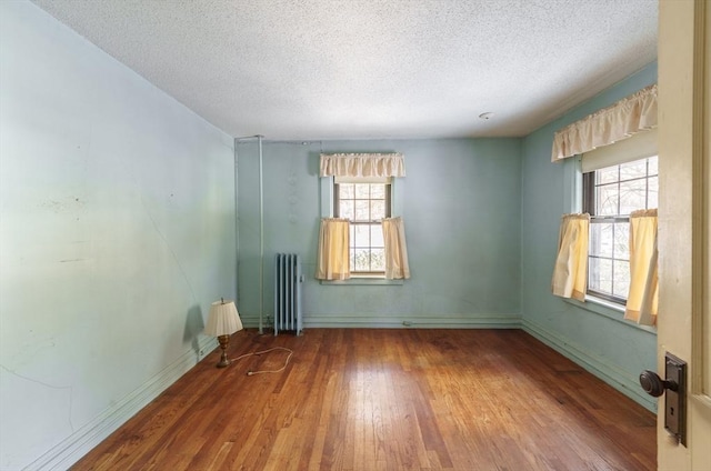 spare room featuring wood-type flooring, radiator, and a textured ceiling