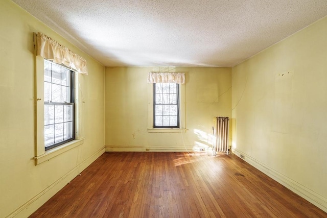 spare room with radiator heating unit, wood-type flooring, and a textured ceiling