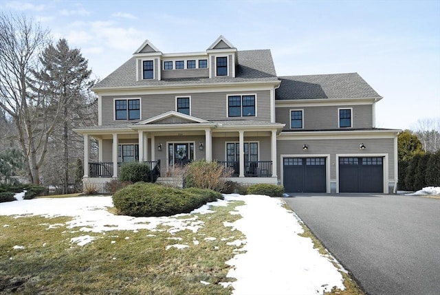 view of front of house featuring aphalt driveway, covered porch, an attached garage, and roof with shingles