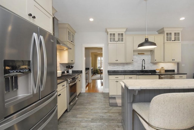 kitchen featuring decorative backsplash, cream cabinets, appliances with stainless steel finishes, and a sink