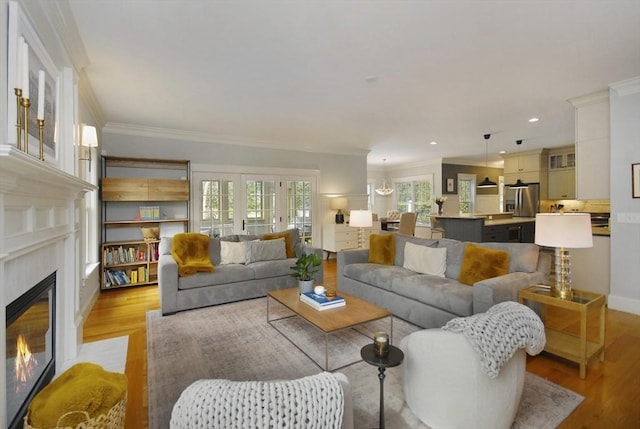 living room featuring light wood finished floors, recessed lighting, a fireplace, and crown molding