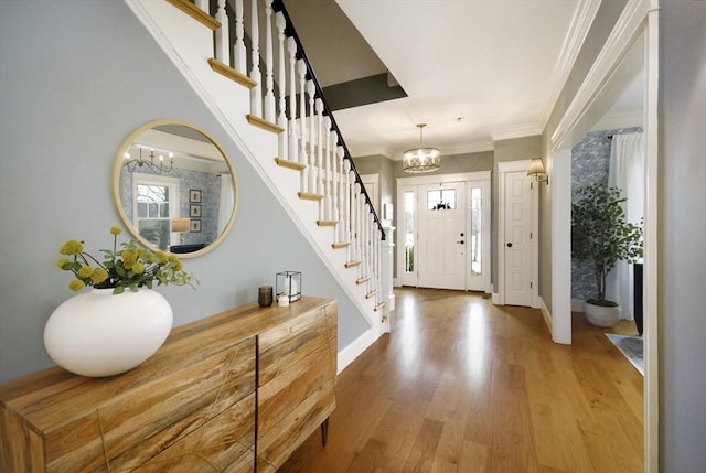 entryway featuring wood finished floors, baseboards, an inviting chandelier, stairs, and crown molding