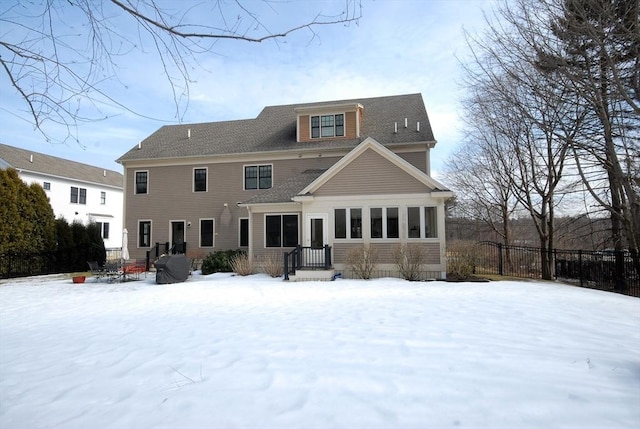 snow covered rear of property with fence