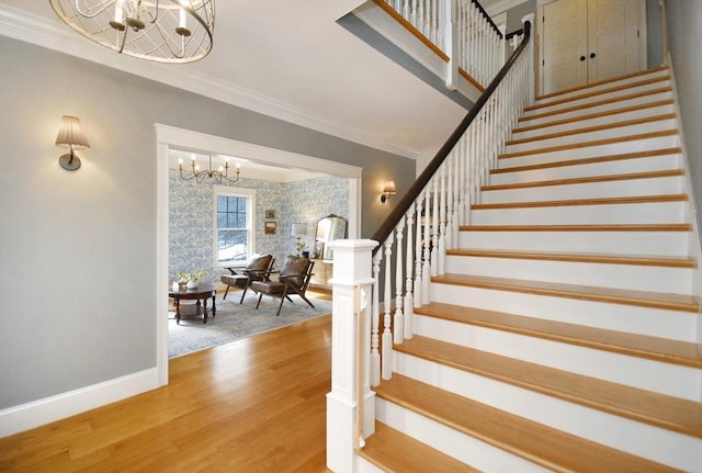 stairs featuring baseboards, wood finished floors, an inviting chandelier, and ornamental molding