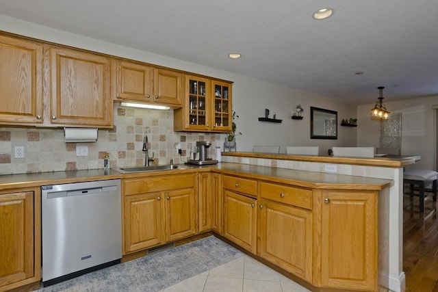 kitchen featuring sink, tasteful backsplash, decorative light fixtures, stainless steel dishwasher, and kitchen peninsula