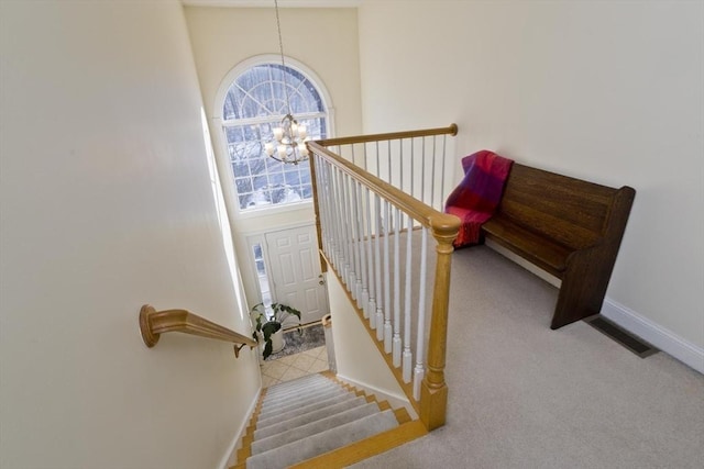 stairs with a towering ceiling, a chandelier, and carpet