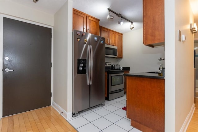 115 Highland Ave Unit 21, Somerville, MA 02143 - kitchen featuring stainless steel appliances, a sink, dark countertops, brown cabinetry, and rail lighting