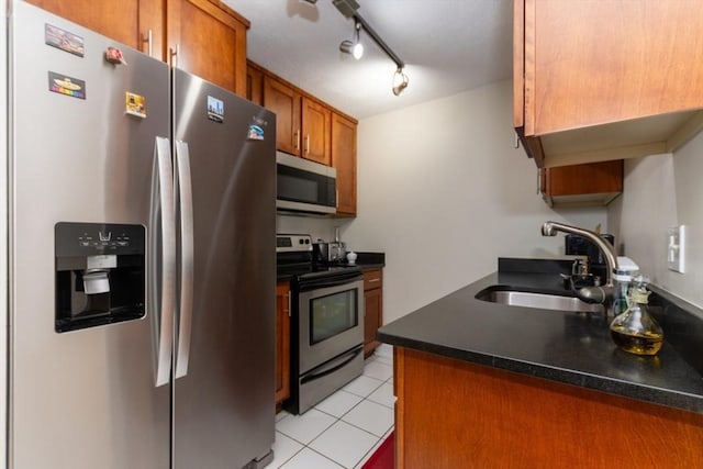 115 Highland Ave Unit 21, Somerville, MA 02143 - kitchen with appliances with stainless steel finishes, a sink, brown cabinetry, dark countertops, and light tile patterned floors