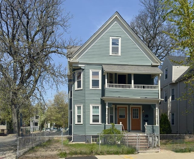 view of front of property featuring a gate, a fenced front yard, a balcony, and covered porch
