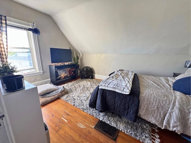 bedroom with wood-type flooring, baseboards, and vaulted ceiling