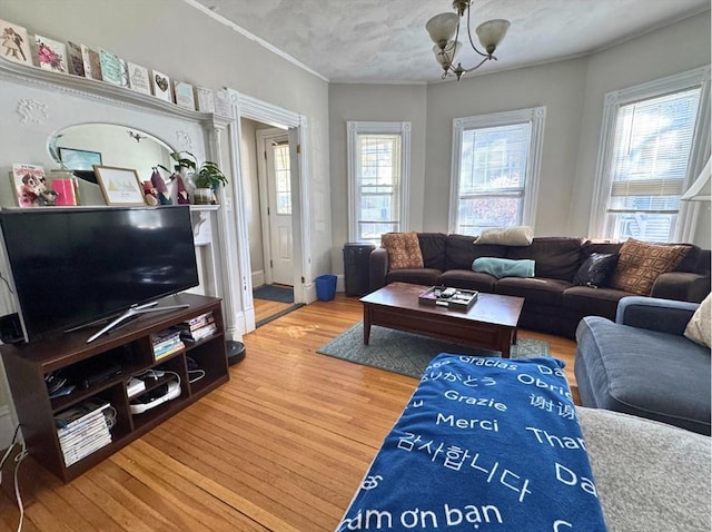 living room with ornamental molding, wood finished floors, and a chandelier