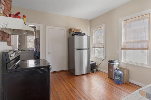 kitchen with plenty of natural light, freestanding refrigerator, electric range, and hardwood / wood-style floors