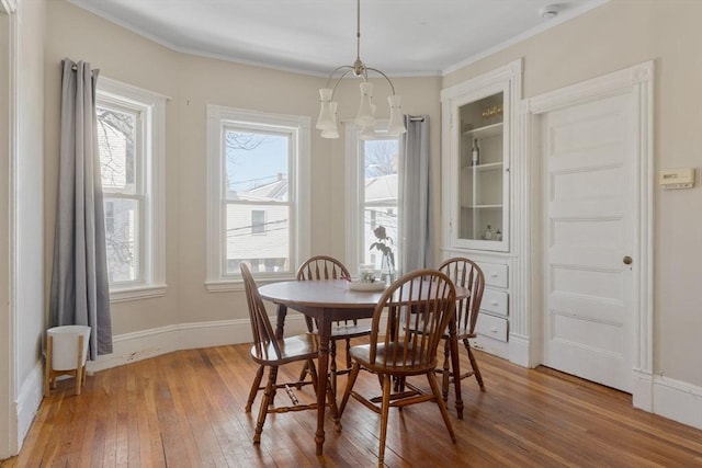 dining space with an inviting chandelier, crown molding, light wood finished floors, and a wealth of natural light
