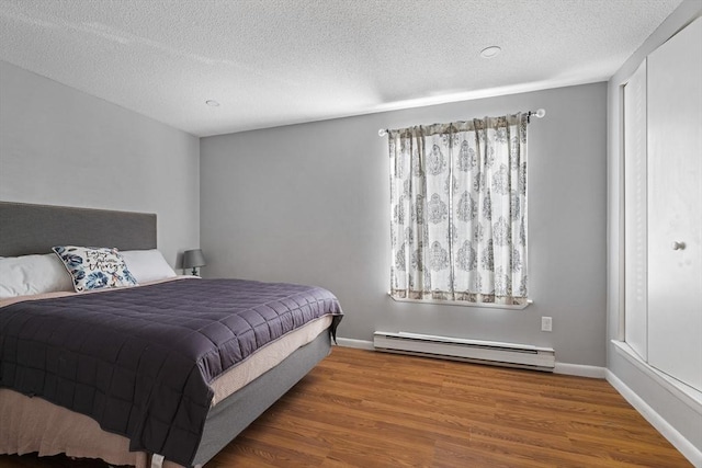 9 Adam St Unit 12, Easton, MA 02375 - bedroom featuring a baseboard radiator, wood finished floors, a textured ceiling, and baseboards