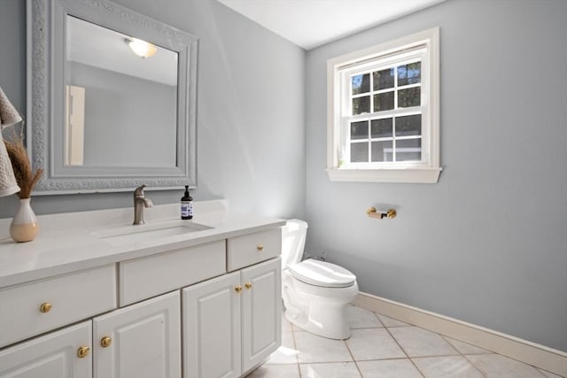 half bathroom with toilet, baseboards, vanity, and tile patterned flooring