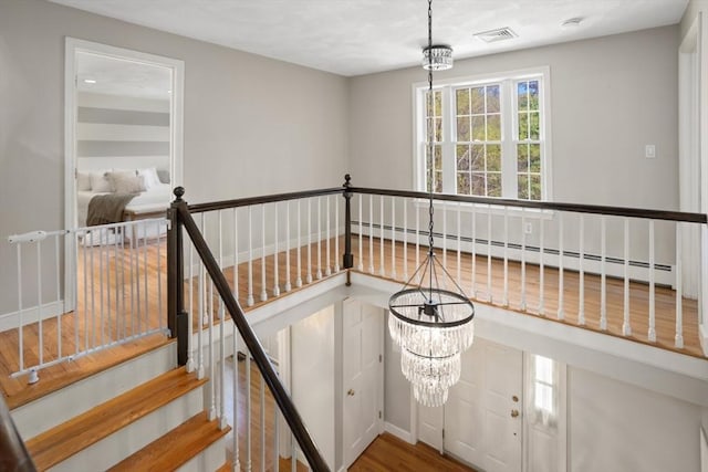 stairway with baseboards, visible vents, and wood finished floors