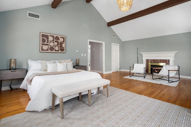 bedroom with beam ceiling, visible vents, wood finished floors, and high vaulted ceiling