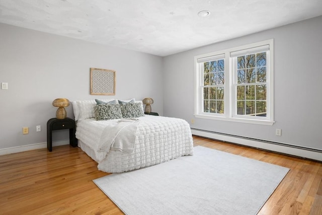 bedroom featuring a baseboard radiator, baseboards, and wood finished floors
