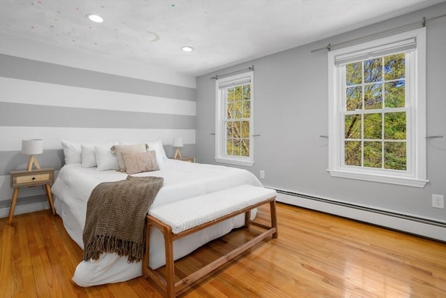 bedroom featuring light wood finished floors, baseboard heating, and recessed lighting