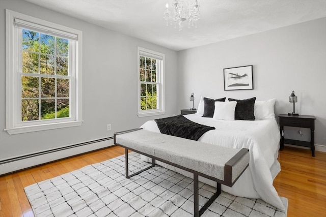 bedroom featuring light wood-style flooring, baseboard heating, and multiple windows