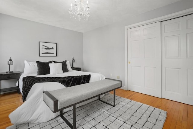 bedroom with light wood-style floors, a closet, and an inviting chandelier