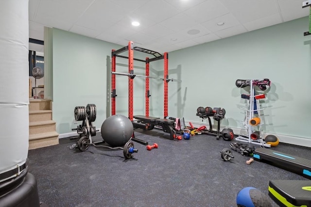 exercise room featuring baseboards and a drop ceiling