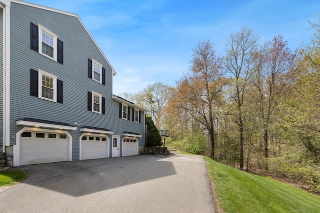 view of side of property featuring aphalt driveway and an attached garage