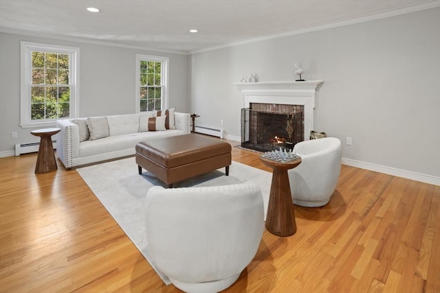living area with a fireplace, crown molding, baseboards, and light wood-type flooring