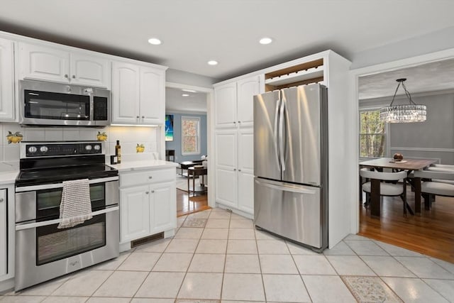 kitchen with an inviting chandelier, white cabinetry, light countertops, light tile patterned floors, and appliances with stainless steel finishes