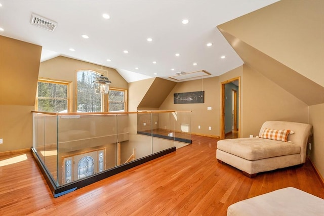 living area with recessed lighting, lofted ceiling, visible vents, an upstairs landing, and wood finished floors