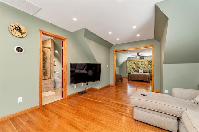 living area featuring light wood-style floors, baseboards, visible vents, and vaulted ceiling