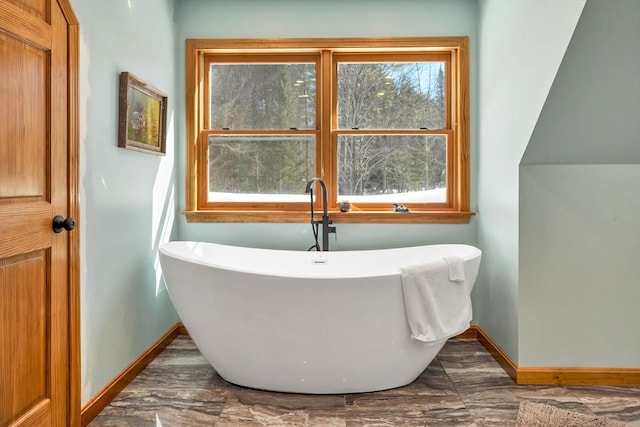 bathroom with a soaking tub and baseboards