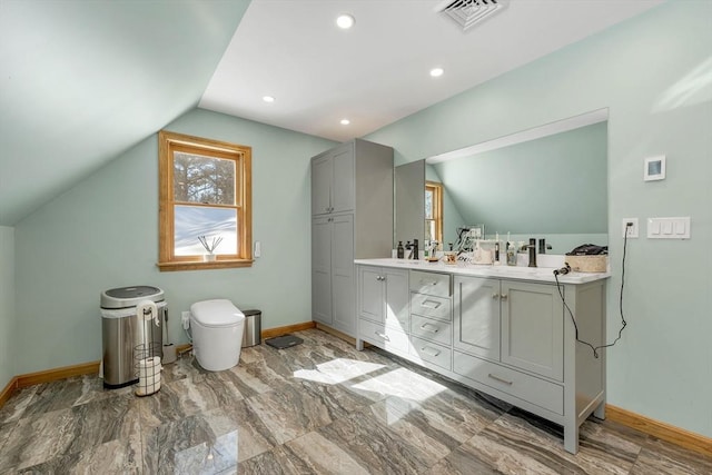 bathroom with lofted ceiling, visible vents, baseboards, and double vanity