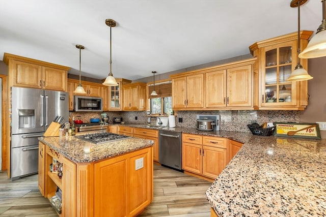 kitchen featuring stone countertops, a kitchen island, stainless steel appliances, and backsplash