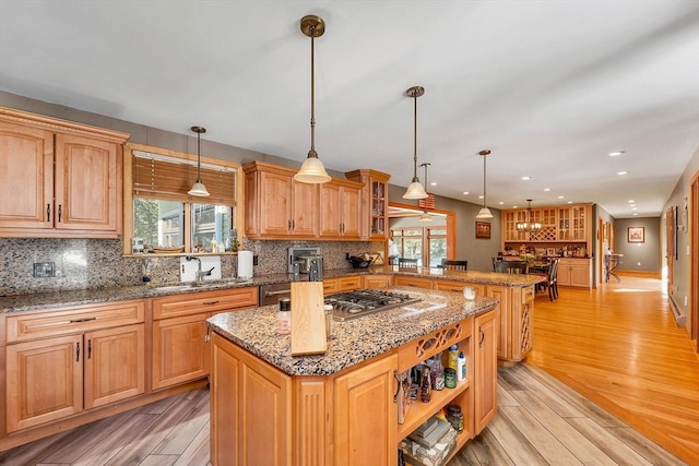 kitchen featuring decorative backsplash, a center island, a peninsula, stainless steel gas stovetop, and a sink