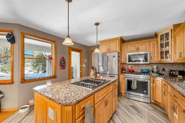 kitchen featuring tasteful backsplash, glass insert cabinets, appliances with stainless steel finishes, light stone counters, and light wood-style floors