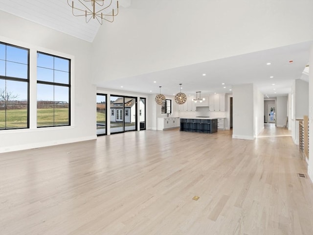 108 Glen St, Natick, MA 01760 - unfurnished living room featuring a chandelier, light wood-type flooring, baseboards, recessed lighting, and a high ceiling