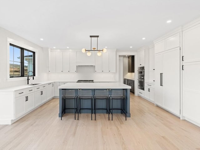 108 Glen St, Natick, MA 01760 - kitchen with a sink, a kitchen bar, a kitchen island, gas cooktop, and white cabinetry