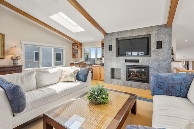 living area featuring a skylight, a large fireplace, and light wood-style floors