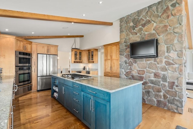 kitchen featuring appliances with stainless steel finishes, a warming drawer, light wood-style floors, a kitchen island, and glass insert cabinets