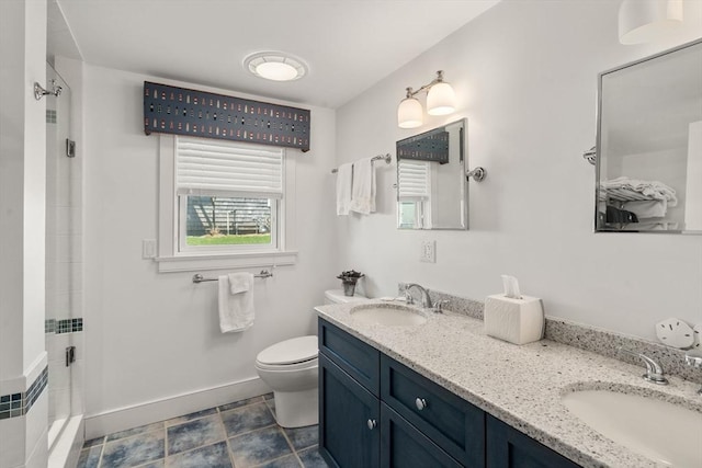 bathroom featuring toilet, a stall shower, double vanity, and baseboards