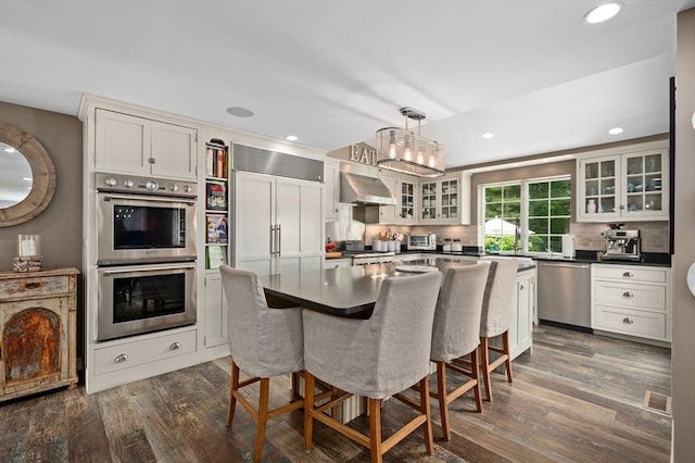 46 Baldpate Rd, Boxford, MA 01921 - kitchen with stainless steel appliances, a kitchen breakfast bar, dark wood-type flooring, tasteful backsplash, and recessed lighting