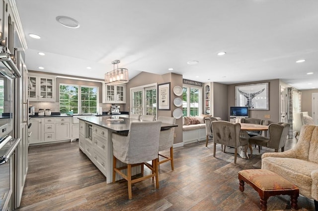 46 Baldpate Rd, Boxford, MA 01921 - kitchen featuring open floor plan, dark countertops, a kitchen breakfast bar, glass insert cabinets, and dark wood finished floors