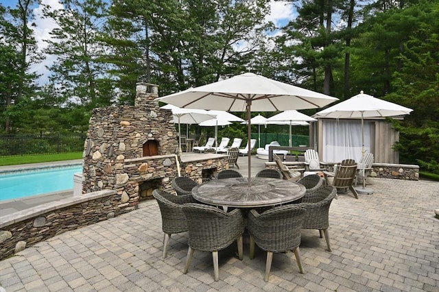 46 Baldpate Rd, Boxford, MA 01921 - view of patio featuring an outdoor stone fireplace, outdoor dining area, and view of wooded area