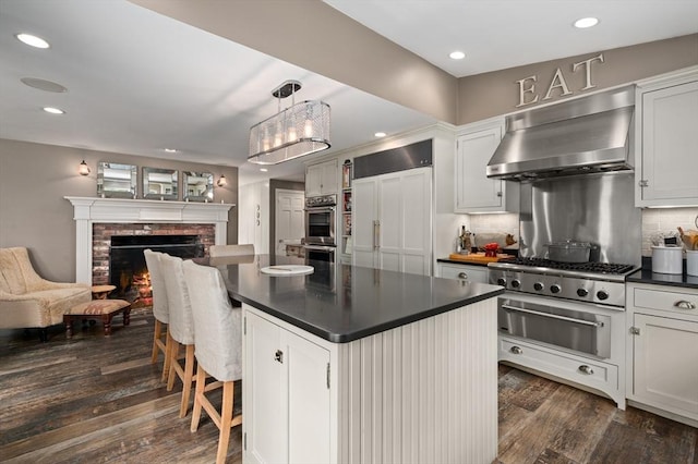 46 Baldpate Rd, Boxford, MA 01921 - kitchen featuring ventilation hood, a warming drawer, appliances with stainless steel finishes, dark countertops, and dark wood-type flooring