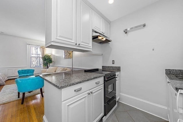 227 Marlborough St Unit 4, Boston, MA 02116 - kitchen with under cabinet range hood, black electric range, white cabinetry, and dark stone countertops