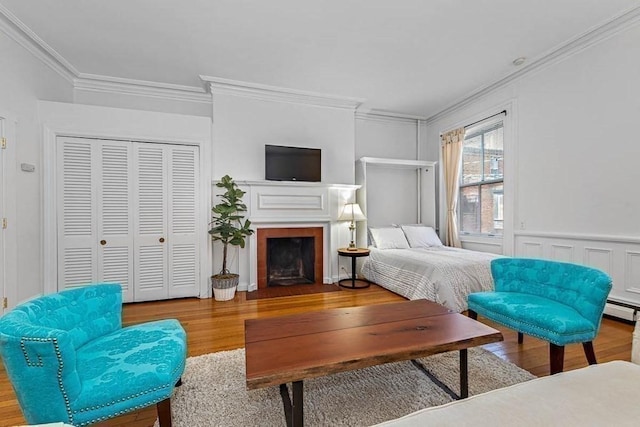 227 Marlborough St Unit 4, Boston, MA 02116 - bedroom with ornamental molding, wood finished floors, a baseboard radiator, a closet, and a fireplace with flush hearth