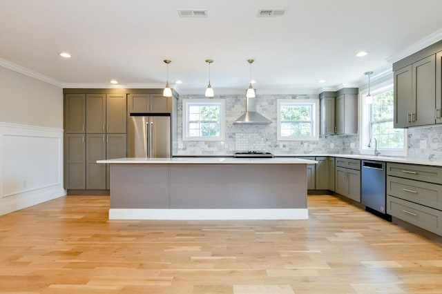 kitchen with appliances with stainless steel finishes, gray cabinetry, a center island, light wood finished floors, and ornamental molding